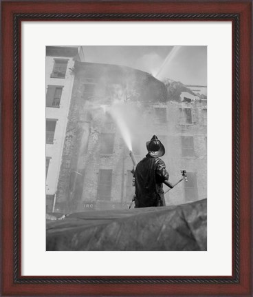 Framed Firefighter pouring water on burning building, low angle view Print