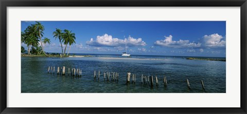 Framed Wooden posts in the sea with a boat in background, Laughing Bird Caye, Victoria Channel, Belize Print