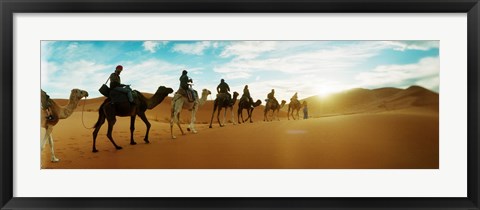 Framed Tourists riding camels through the Sahara Desert landscape led by a Berber man, Morocco Print