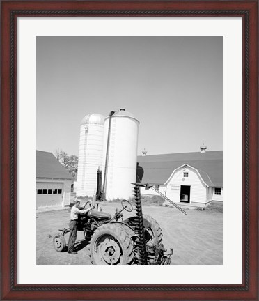 Framed USA, Farmer Working on Tractor, Agricultural Buildings in the Background Print