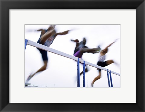 Framed Low angle view of three men jumping over a hurdle Print