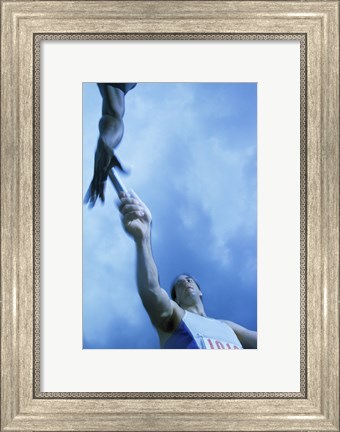 Framed Low angle view of runners passing a baton in a relay race Print