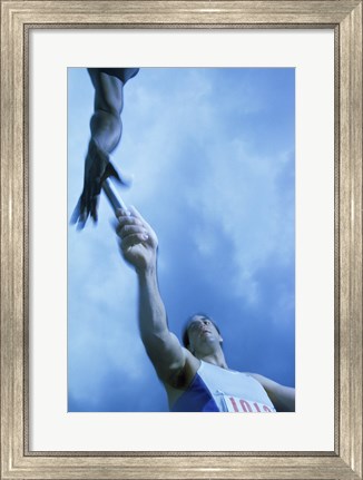 Framed Low angle view of runners passing a baton in a relay race Print
