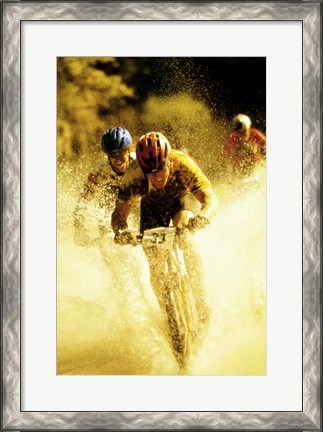 Framed Young men riding bicycles through water Print