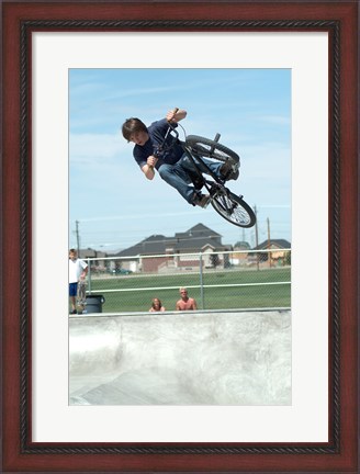 Framed Low angle view of a teenage boy performing a stunt on a bicycle over ramp Print