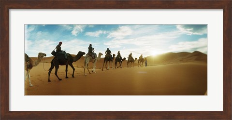 Framed Tourists riding camels through the Sahara Desert landscape led by a Berber man, Morocco Print