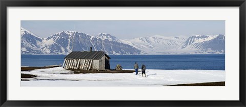 Framed Two hikers standing on the beach near a hunting cabin, Bellsund, Spitsbergen, Svalbard Islands, Norway Print