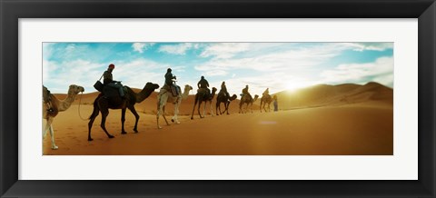 Framed Tourists riding camels through the Sahara Desert landscape led by a Berber man, Morocco Print