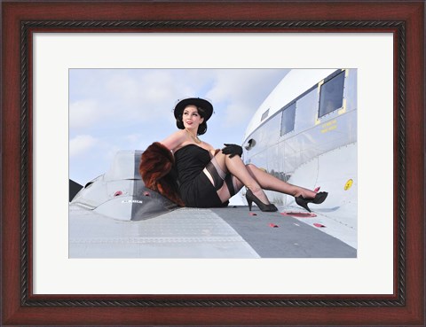 Framed Glamorous woman in 1940&#39;s style attire sitting on a vintage aircraft Print