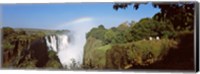 Framed Tourists at a viewing point looking at the rainbow formed over Victoria Falls, Zimbabwe