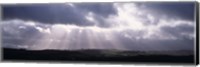 Framed Sunbeams radiating through dark clouds over rolling hills, Dartmoor, Devon, England