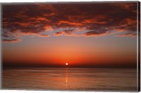 Framed layer of clouds is lit by the rising sun over Rio de la Plata, Buenos Aires, Argentina