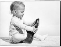 Framed 1960s Baby Boy Trying To Put On Man'S Shoe