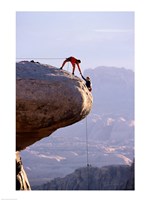 Framed Side profile of a young man pulling a young woman onto a rock