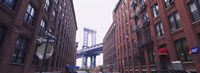 Framed Low angle view of a suspension bridge viewed through buildings, Manhattan Bridge, Brooklyn, New York City, New York State, USA