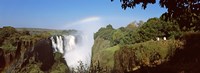 Framed Tourists at a viewing point looking at the rainbow formed over Victoria Falls, Zimbabwe