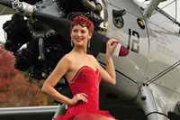 Framed Redhead pin-up girl in 1940's style dancer attire holding on to a vintage aircraft propeller