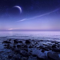 Framed Moon rising over rocky seaside against starry sky