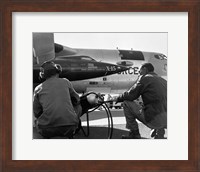 Framed Rear view of two men crouching near fighter planes, X-15 Rocket Research Airplane, B-52 Mothership