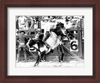 Framed Side profile of a cowboy riding a bull at a rodeo