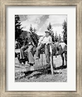 Framed Teenage cowboys sitting on rail fence