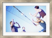 Framed Low angle view of two young couples playing beach volleyball