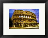 Framed Low angle view of the old ruins of an amphitheater lit up at dusk, Colosseum, Rome, Italy