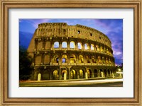 Framed Low angle view of the old ruins of an amphitheater lit up at dusk, Colosseum, Rome, Italy