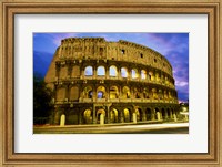 Framed Low angle view of the old ruins of an amphitheater lit up at dusk, Colosseum, Rome, Italy