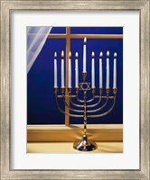 Framed Close-up of burning candles on a menorah at a window