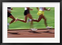 Framed Low section view of male athletes running on a running track