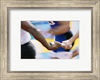 Framed Mid section view of runners exchanging baton at a relay race