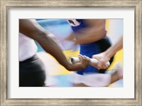 Framed Mid section view of runners exchanging baton at a relay race