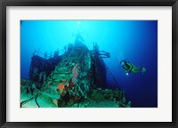 Framed Scuba diver watching a shipwreck underwater