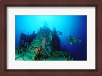 Framed Scuba diver watching a shipwreck underwater