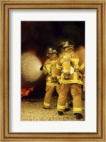 Framed Rear view of three firefighters extinguishing a fire