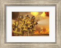 Framed Rear view of a group of firefighters extinguishing a fire and flames