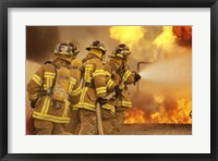 Framed Rear view of a group of firefighters extinguishing a fire and flames