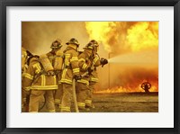 Framed Rear view of a group of firefighters extinguishing a fire