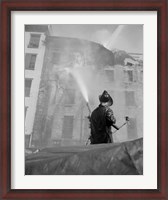 Framed Firefighter pouring water on burning building, low angle view