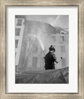 Framed Firefighter pouring water on burning building, low angle view