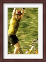 Framed Young man sitting on a bicycle with his arms raised