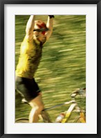 Framed Young man sitting on a bicycle with his arms raised