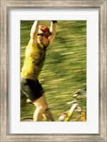 Framed Young man sitting on a bicycle with his arms raised