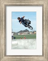 Framed Low angle view of a teenage boy performing a stunt on a bicycle over ramp