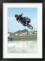 Low angle view of a teenage boy performing a stunt on a bicycle over ramp Framed Print
