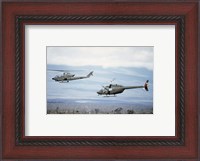 Framed left side view of an AH-1 Cobra helicopter, front, and an OH-58 Kiowa helicopter