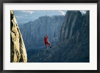 Framed Rear view of a man rappelling down a rock