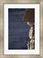 Framed Man hanging from a rope on the edge of a cliff
