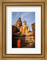 Framed Monk praying in front of a statue of Buddha